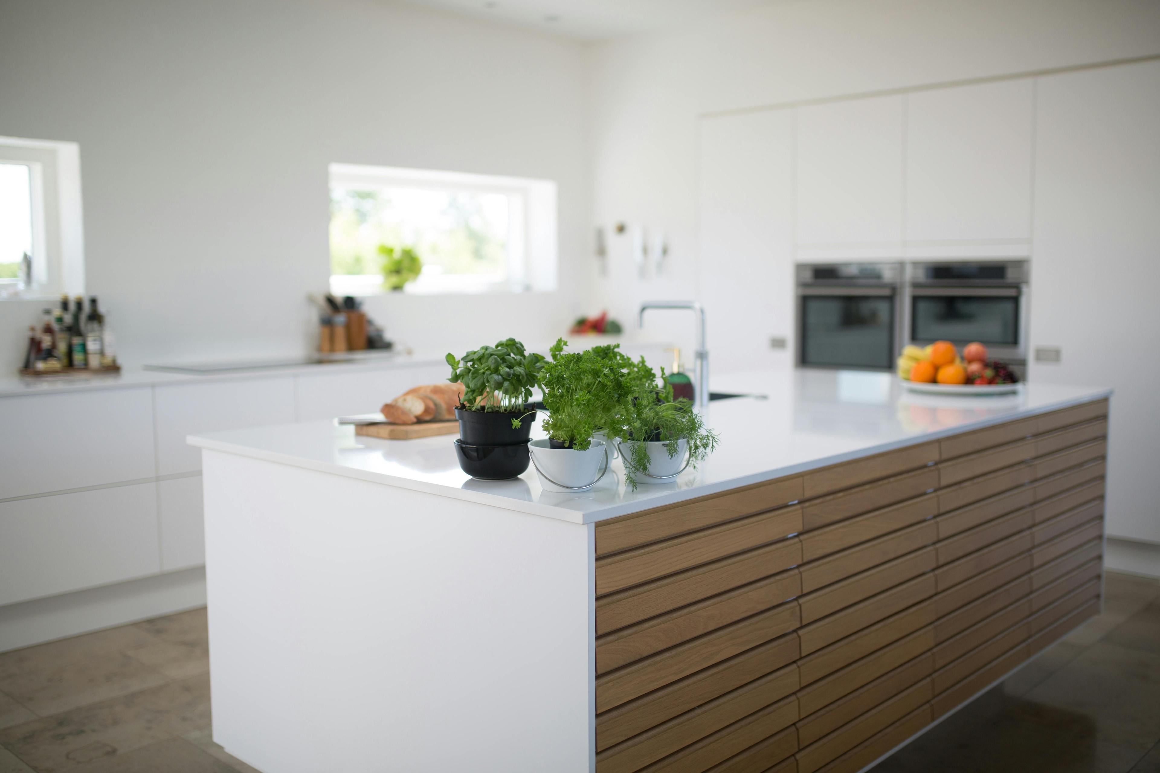 Moderne Küche mit großer Arbeitsplatte aus Dekton, Holzfronten und weißen Schränken im Hintergrund.